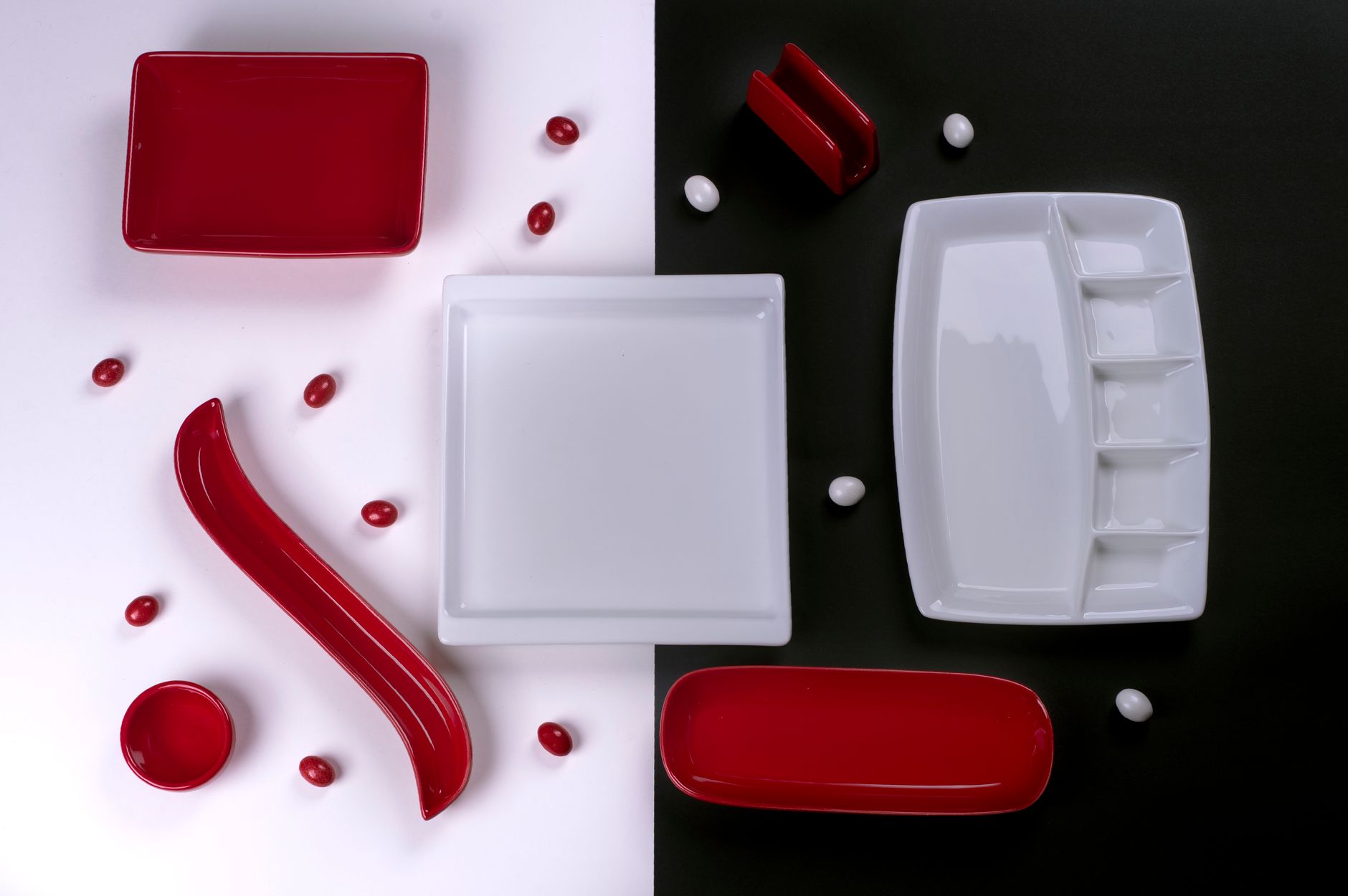 A stylish flat lay of red and white porcelain tableware on contrasting backgrounds, perfect for modern decor.