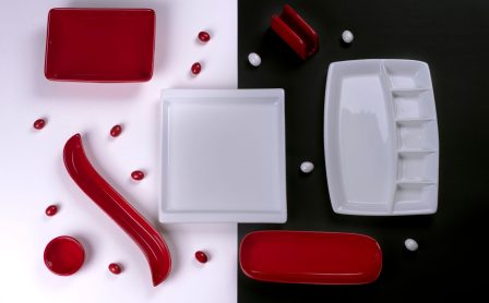 A stylish flat lay of red and white porcelain tableware on contrasting backgrounds, perfect for modern decor.